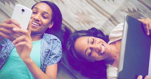 Mother and daughter laying on carpet using cell phone and digital tablet