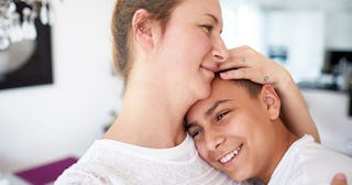 Mother and teenage son embracing at home