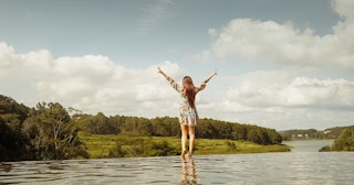 how to enjoy life, Woman with arms up standing in shallow water
