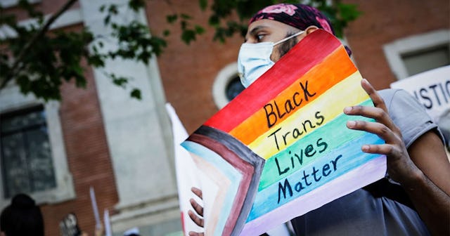 Black Trans Women's Lives Matter — Let's Show Up For Them: A participant holds up a '-black Trans Li...
