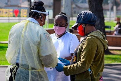 Local residents Burnetta Kinsey (C) and Zina Parker (R) fill out paperwork at a mobile COVID-19 test...