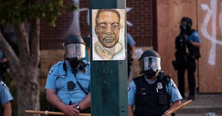 A portrait of George Floyd hangs on a street light pole as police officers stand guard at the Third ...