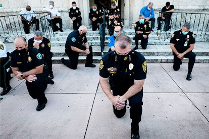 Police officers kneel during a rally in Coral Gables, Florida on May 30, 2020 in response to the rec...