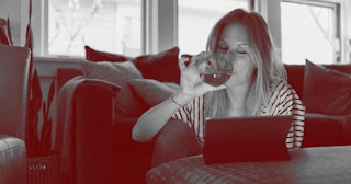 Woman drinking wine and looking at tablet at home