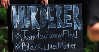 A demonstrator holds a placard during a protest outside a home owned by Derek Chauvin, the Minneapol...