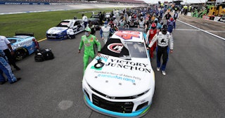 NASCAR drivers push the #43 Victory Junction Chevrolet, driven by Bubba Wallace, to the front of the...