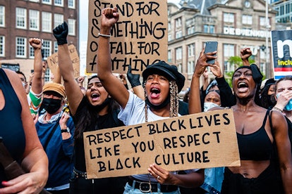 black woman is screaming while holding a big placard, during the massive solidarity protest against ...