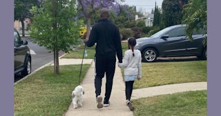 A father and his daughter walking their dog down a pedestrian