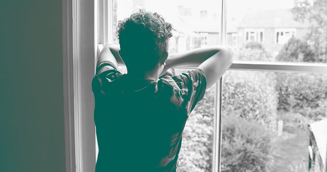 Teenage boy looking out of bedroom window