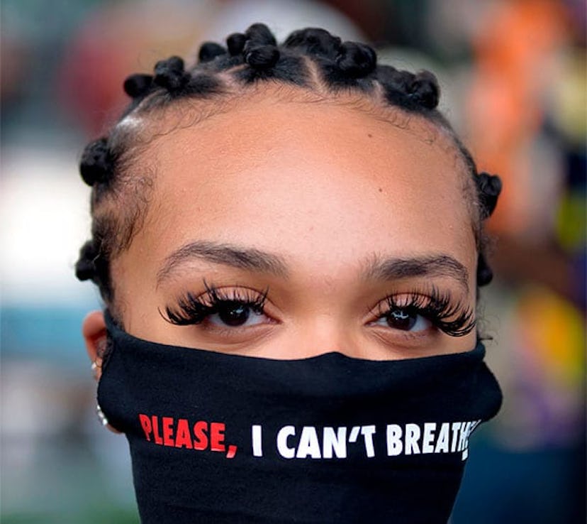 A woman wears a facemask reading "Please, I can't breathe" during a "Justice for George Floyd" event...