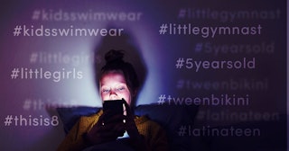 A young teenager is sitting in her bed in the dark with only the light of her phone shining on her f...