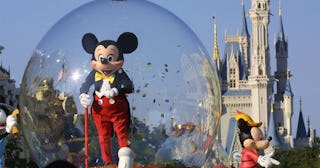 Mickey Mouse rides in a parade through Main Street, USA with Cinderella's castle in the background a...