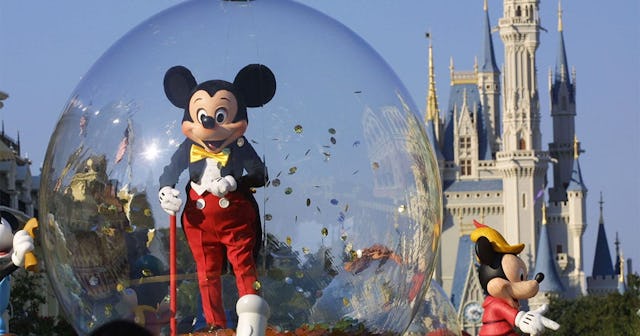 Mickey Mouse rides in a parade through Main Street, USA with Cinderella's castle in the background a...