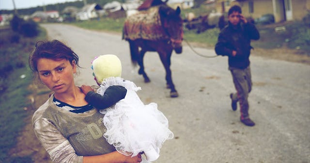 oung Roma mother Claudia Varga holds her infant daughter Raluca on the only street in the abjectly p.