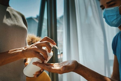 Wife poring some hand sanitizer into her husband's hands