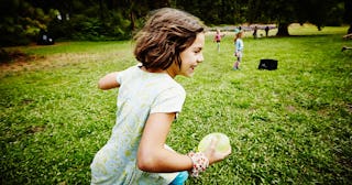 Girl running through field with water balloon