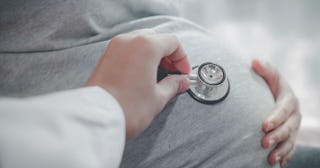 Cropped Hand Of Doctor Examining Pregnant Woman Belly With Stethoscope