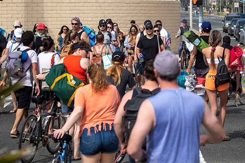 With beach parking lots closed down, crowds of people cross Pacific Coast Highway to and from the be...