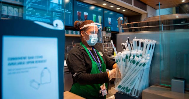 A Starbucks employee wears a face shield and mask as she makes a coffee in Ronald Reagan Washington ...