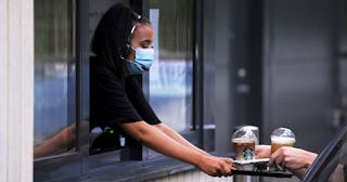 A member of staff hands a customer their drinks through a window at a Starbucks drive-through on the...