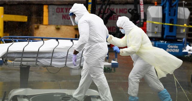 Medical personnel move a deceased patient to a refrigerated truck serving as make shift morgues at B...