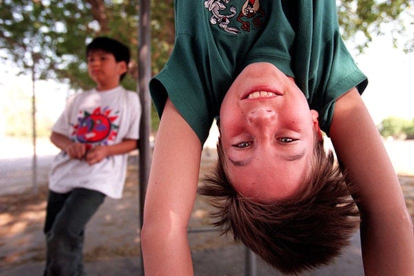 boy Hanging upside down from some playground equipment