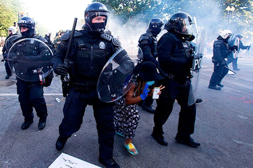 A demonstrator try to pass between a police line wearing riot gear as they push back demonstrators o...