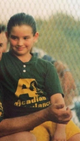 Young Allison LaCombe wearing a green t-shirt and yellow shorts, smiling