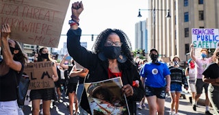 Hope Coleman holds up her fist as she marches with other demonstrators after gathering outside of Su...