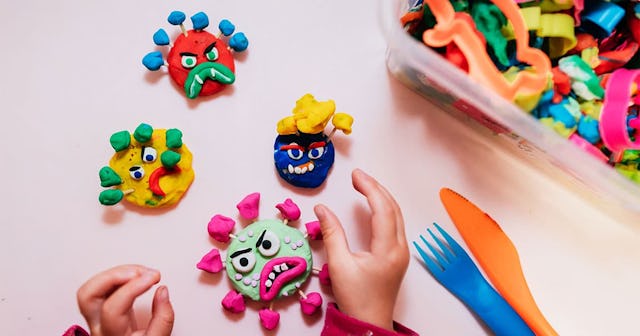 Child playing with plasticine at home making virus