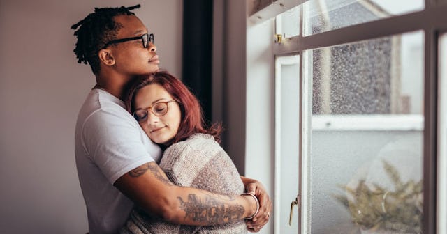 Interracial couple hugging near window