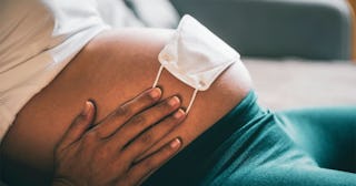 Pregnant woman protecting her baby with a face mask on her belly