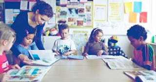 Teacher looking in books with children