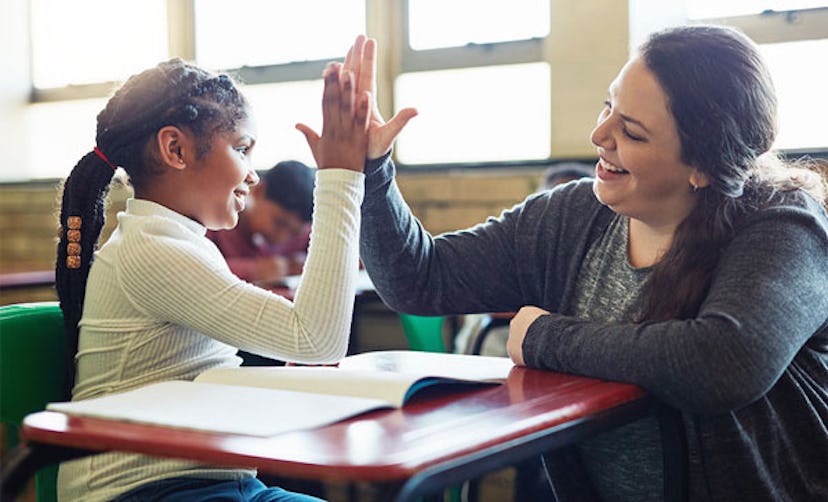 Shot of a young girl giving her teacher a high five in a classroom
