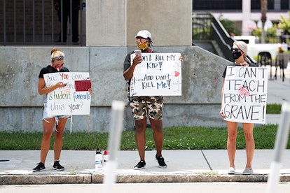 School counselor Chloe Gerbec, teachers Malikah Armbrister, and Brittany Myers stand in protest in f...