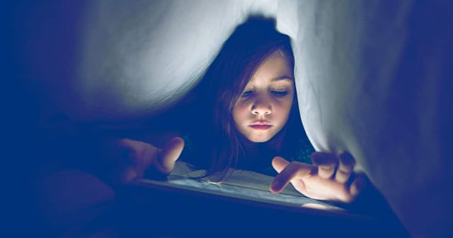 girl using wireless tablet under the bed covers