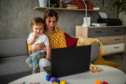 Mother trying to stay concentrated for work while holding her son in lap