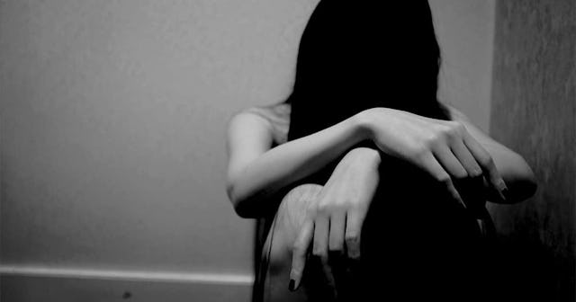 woman sitting with hair over face against wall