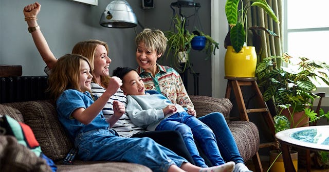 family with two kids watching television and smiling