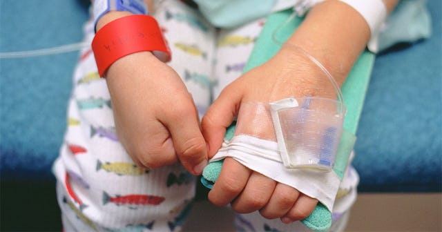 Young boy in hospital bed showing intravenous lines in arm