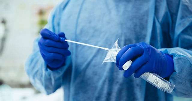 Close-up of emergency doctor putting a swab into a tube in hospital