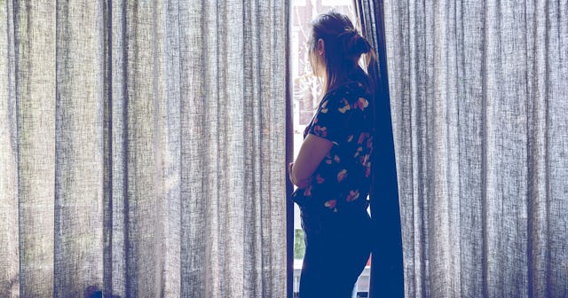 Woman looking outside the window during quarantaine