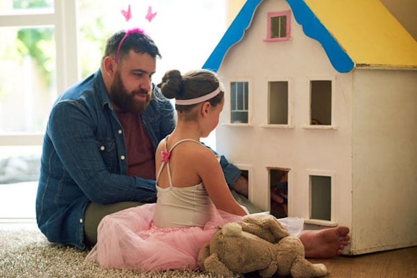 little girl and her father playing with a dollhouse together at home