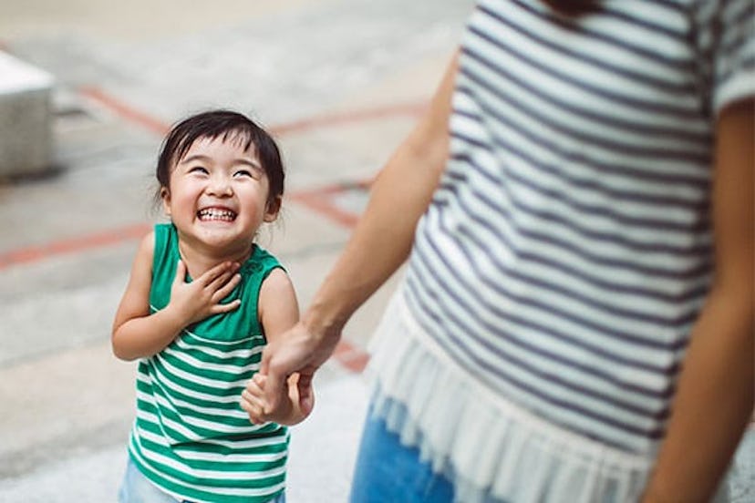 Smiling toddler holding hands with mom in park