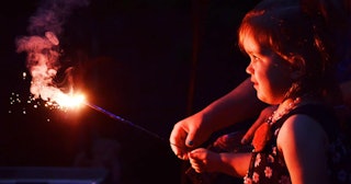girl watching lighting of sparklers