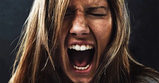woman screaming uncontrollably while isolated on a black background