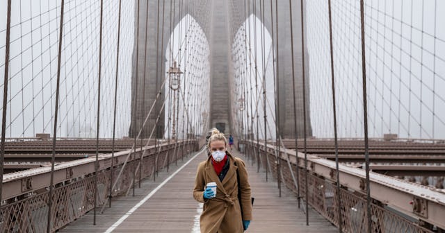 A woman wearing a mask walks the Brooklyn Bridge in the midst of the coronavirus outbreak on March 2...