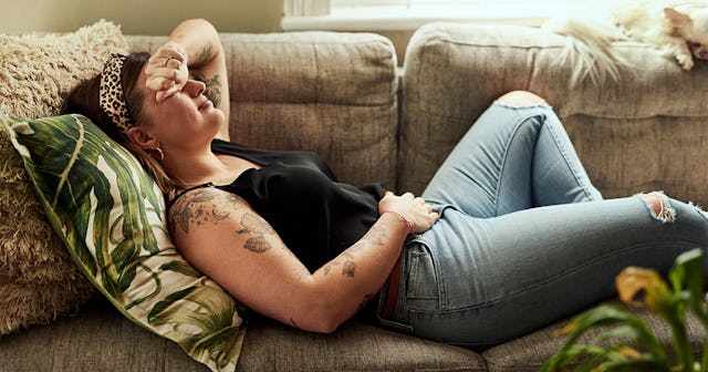 woman suffering from stomach cramps on the sofa at home