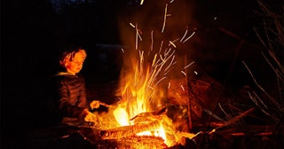 boy at camp fire at night