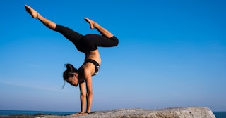thigh toner exercises, Woman doing handstand on rock